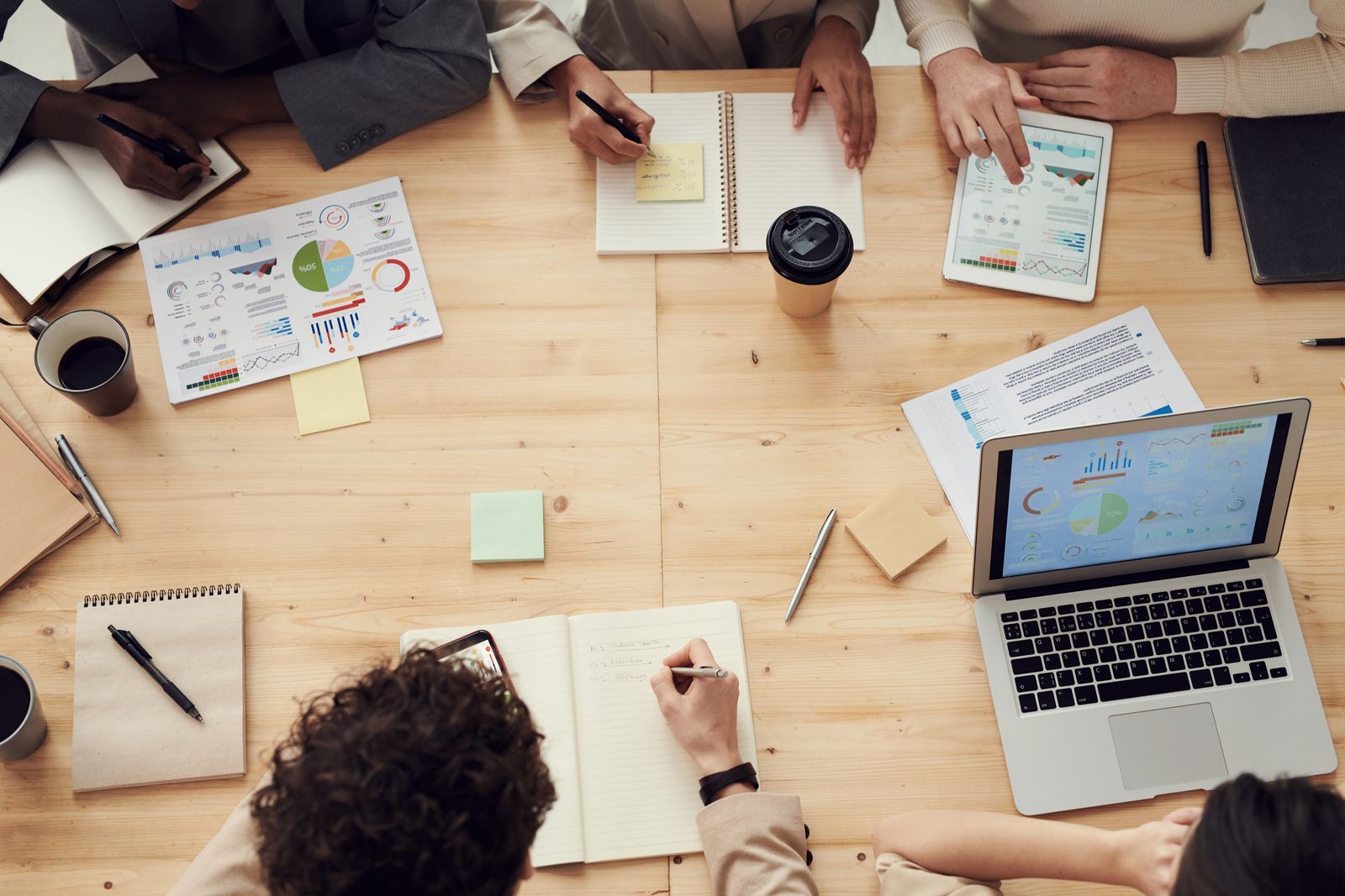 A team in a meeting reviewing project charts and plans around a table