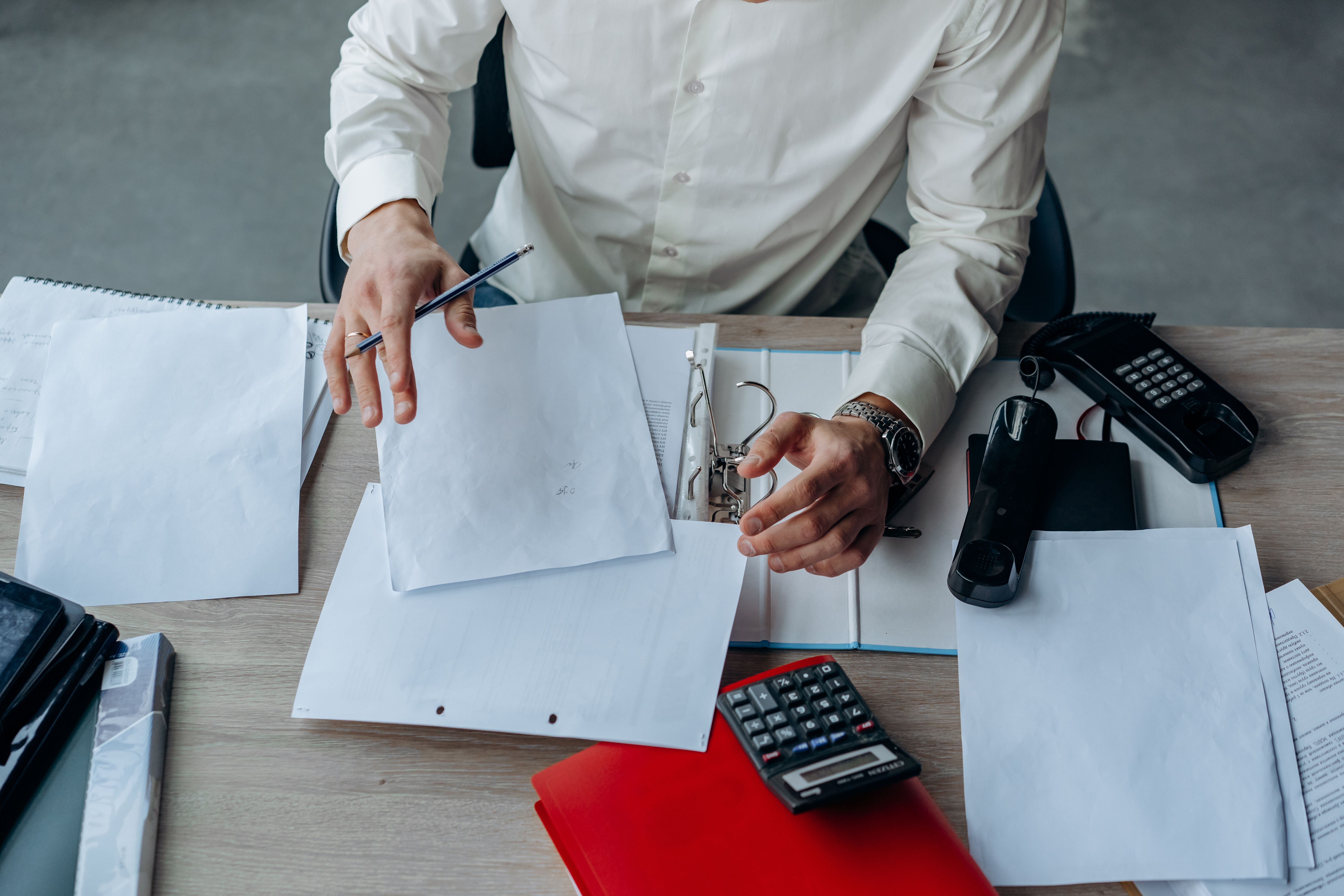 A business professional organizing documents at an office desk for efficient workflow