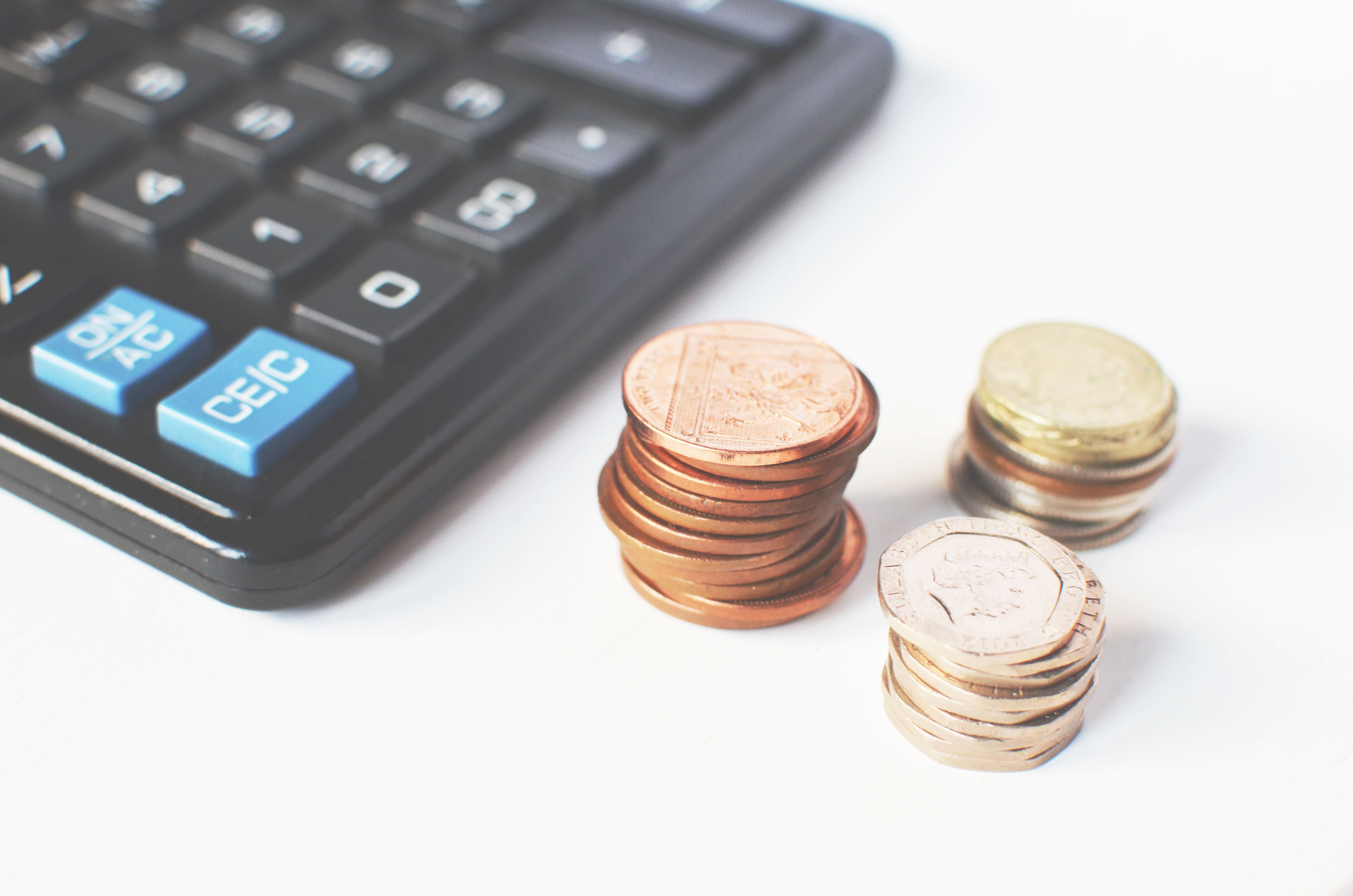 Stacked coins and a calculator on a desk symbolizing pricing strategy decisions