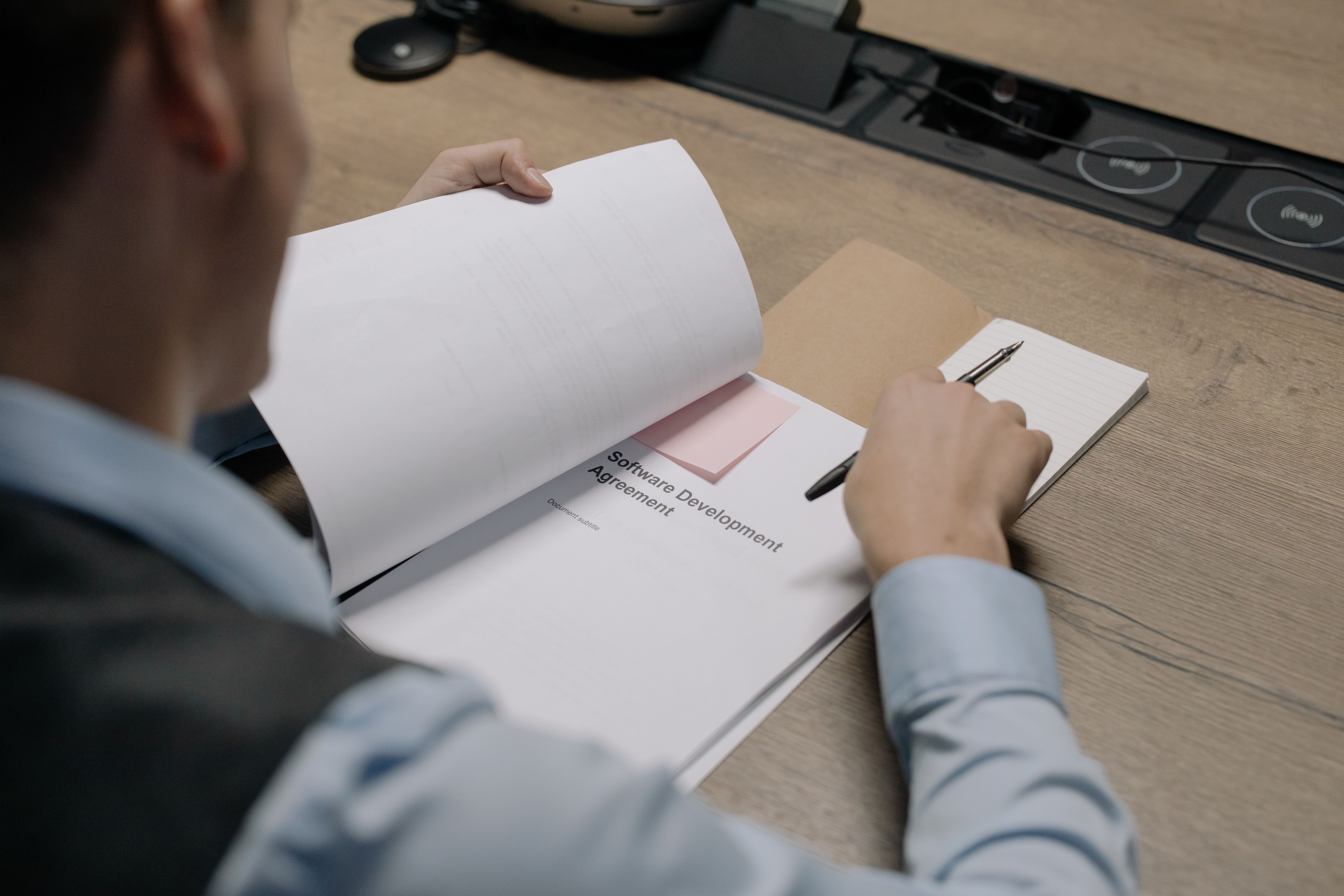 Business professional reviewing a software development proposal document at the office